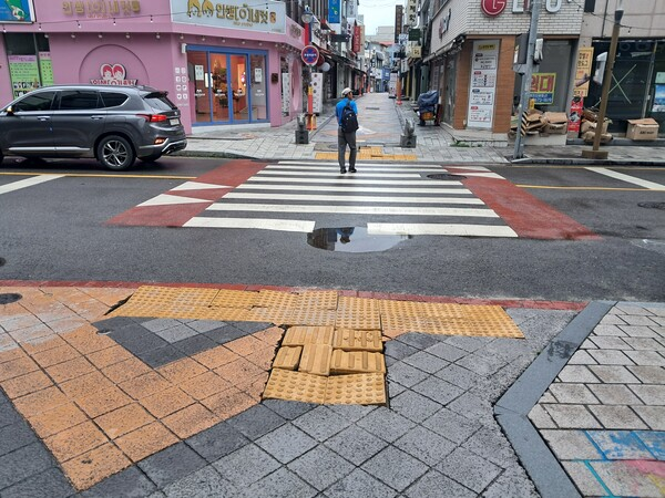 순천시 중앙동 도로모습으로 시각장애인 통행을 안내하는 보도블럭이 움푹 패여있으며 횡단보도에는 빗물이 고여 있다[사진=이종철 기자]